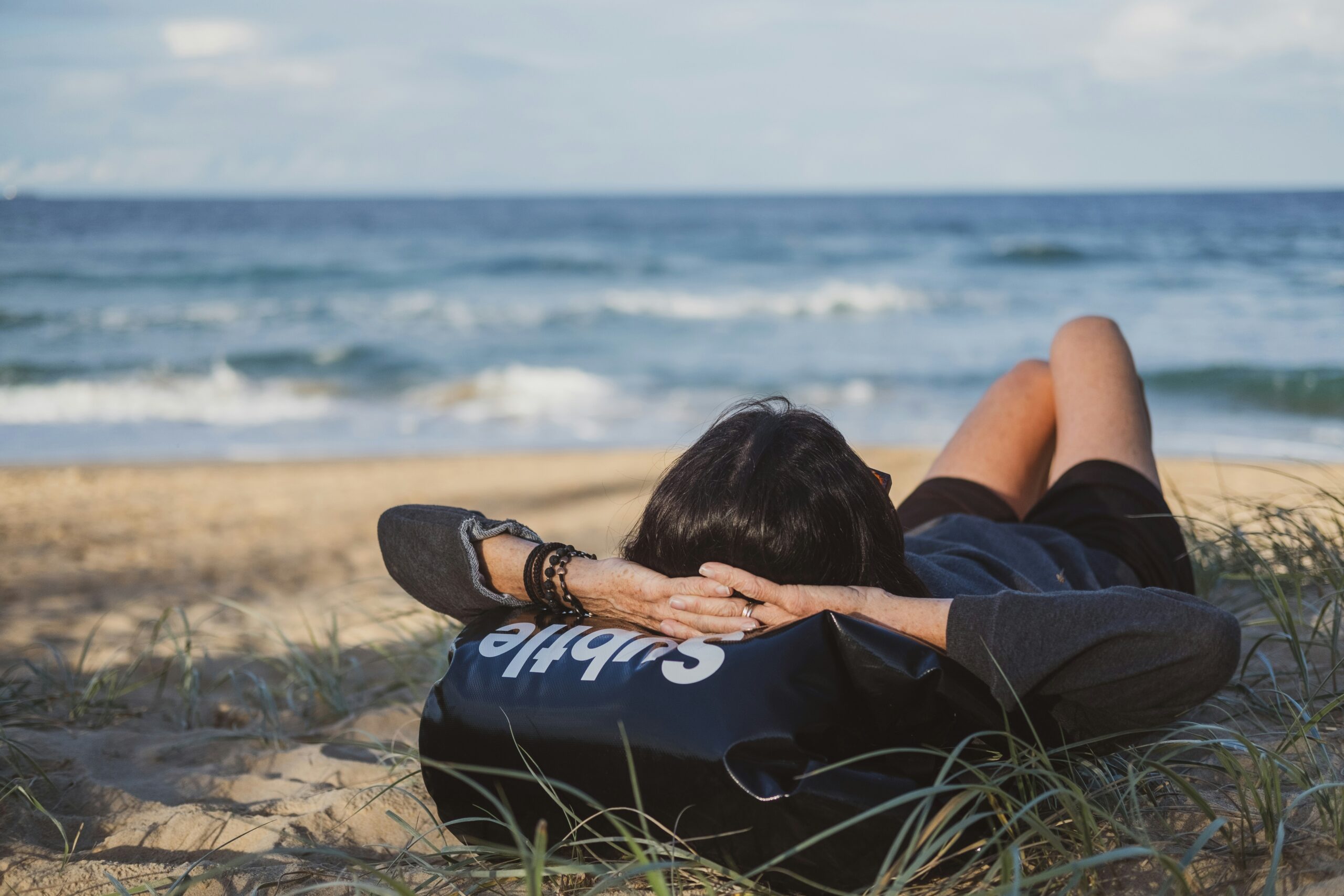 women lounging in beach with hands behind head